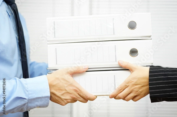 Fototapeta Client is passing documentation in binders to his partner