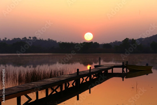Obraz African landscape. The sun rising over the lake and the boat tied to the dock
