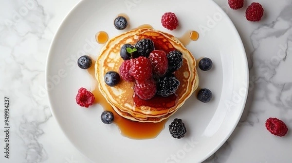 Fototapeta A plate of pancakes with berries and syrup on top