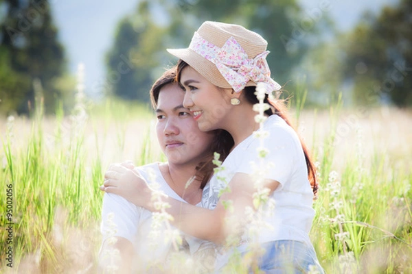 Fototapeta Young couple in love hugging and sitting in the meadow
