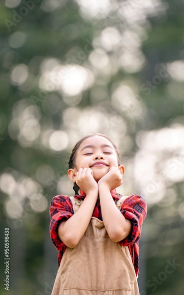 Obraz A little girl is walking in the garden and breathing in the fresh air.