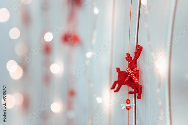 Fototapeta new year's and christmas decoration of a red deer hanging on a wooden texture wall with lights