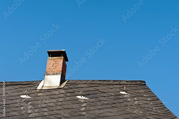 Fototapeta Gemauerter Schornstein mit Kaminaufsatz in einem Schieferdach