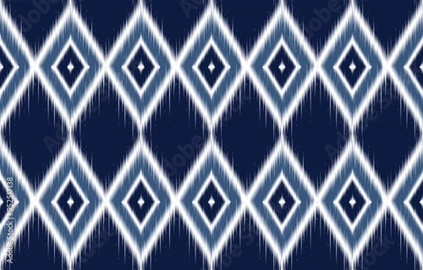Fototapeta Navy and white ikat-inspired pattern. Blurred diamond shapes create geometric pattern. Traditional weaving pattern reimagined. Suitable for fabric, wallpaper, and digital designs. Seamless ethnic.