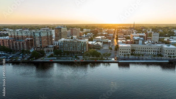 Fototapeta Aerial view of historic downtown Wilmington, NC, with buildings reflecting the sunrise over the Cape Fear River.