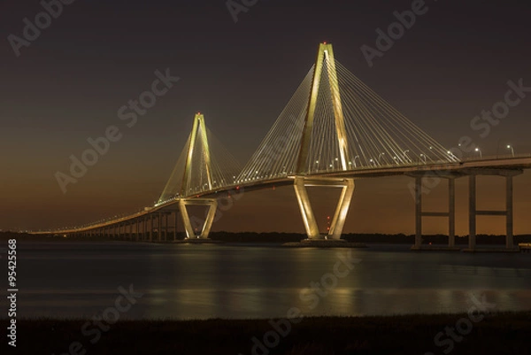 Fototapeta Arthur Ravenel Jr. Bridge illuminated aginst a darkening dusk sky.  The bridge carries eight lanes of traffic over the Cooper River between Charleston and Mount Pleasant, SC.
