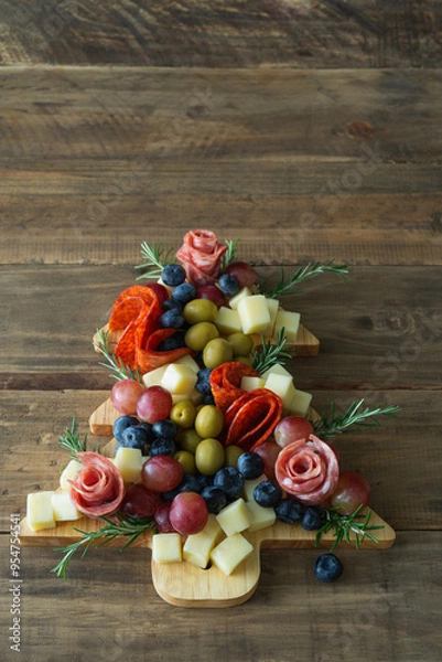 Fototapeta A wooden tray with a tree shape is filled with various types of food. Vertical photo.