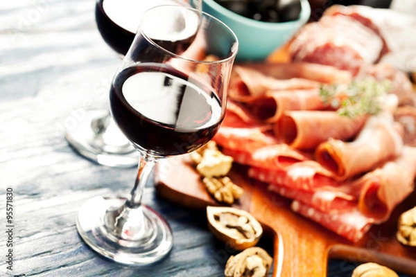 Fototapeta Red wine with charcuterie assortment on the background