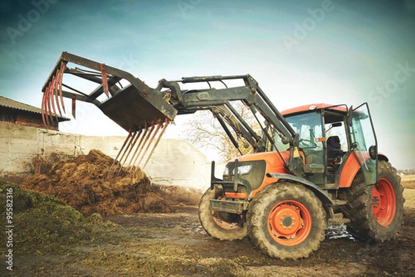 Fototapeta Dirty agricultural tractor with grasper for dung ready to work
