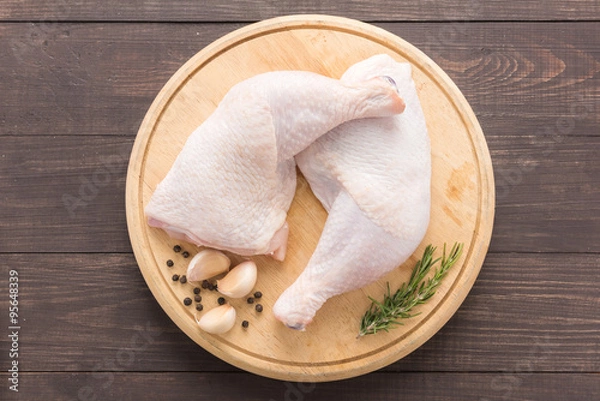 Obraz Raw chicken leg on cutting board on wooden background