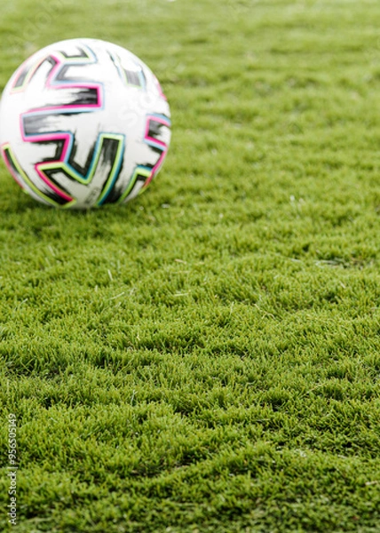 Fototapeta  Green Artificial Grass with a Blurred Colourful Football in the Background