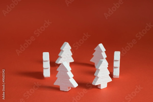 Fototapeta White christmas trees made of wood placed placed in a circle on a red background.