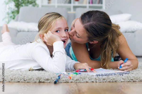 Fototapeta Young mother and daughter drawing on the notebook at home.