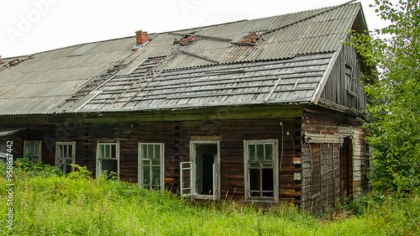 Fototapeta broken windows of an abandoned village house overgrown with grass