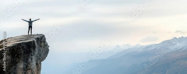 Fototapeta Person standing at the edge of a cliff with arms outstretched, ready for a new beginning