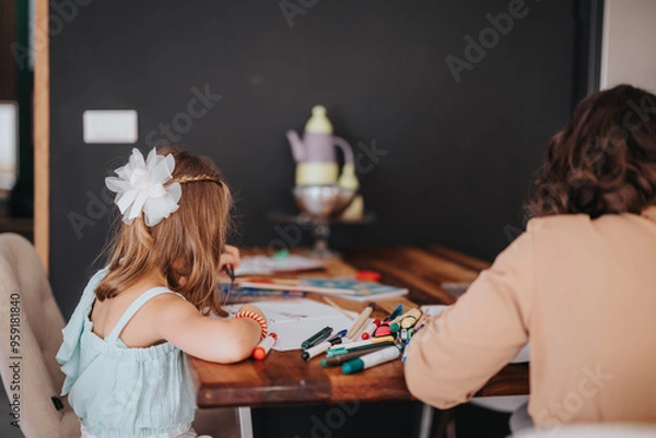 Fototapeta A loving mother and daughter enjoy a creative drawing session at home. The image captures the warmth and togetherness of family time in a cozy, artistic setting.