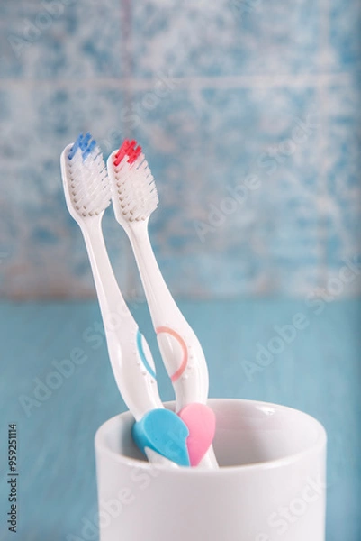 Fototapeta Toothbrushes in the shape of a heart in a glass on a colored background