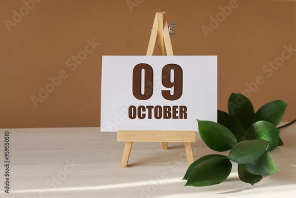 Fototapeta October 9th. Day 9 of month, Calendar date. Green branch, easel with the date and month on desktop. Close-up, brown background. Autumn month, day of year concept