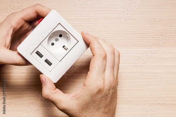 Obraz A man installs the decorating pane to  the socket with two usb c
