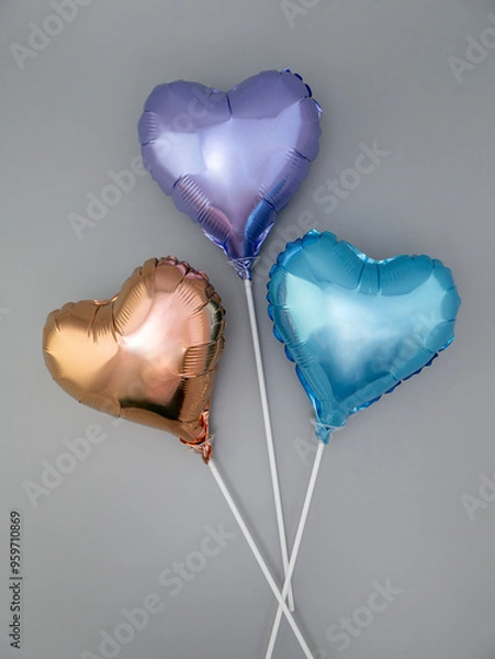 Fototapeta Three foil heart-shaped balloons on a stick on a gray background