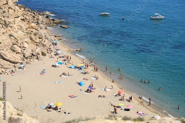 Fototapeta View of La Plagette, a Mediterranean beach bordered by cliffs near Leucate, France featuring golden sands and translucent water with people swimming and sunbathing and boats visible near shore