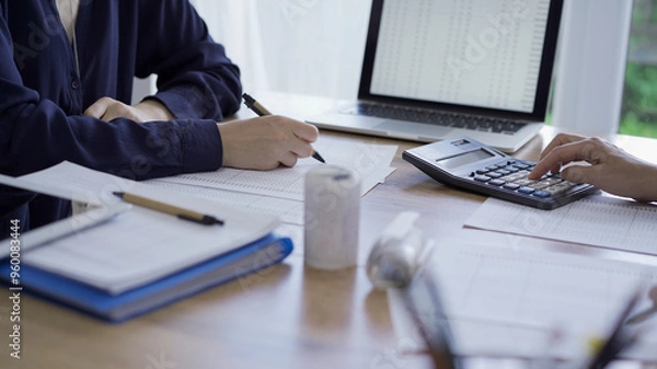 Fototapeta Accountants or auditors reviewing financial documents while sitting opposite one another at the wooden desk in office. Audit and taxes