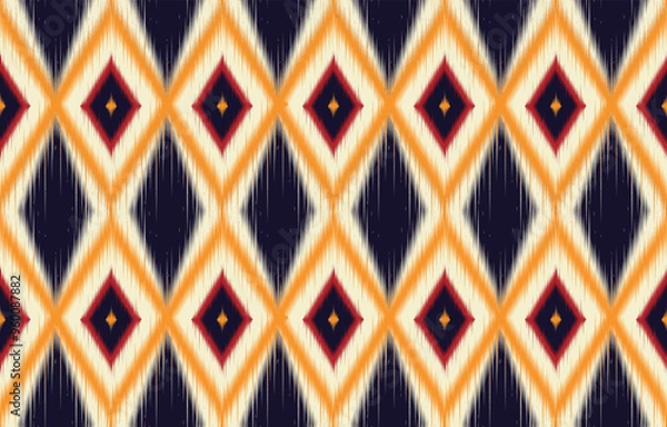 Fototapeta Colorful ikat diamond pattern. Seamless ethnic print with vibrant orange and navy. Trendy geometric tribal texture for fabric. Abstract bohemian background. Modern ikat design for stylish decor.