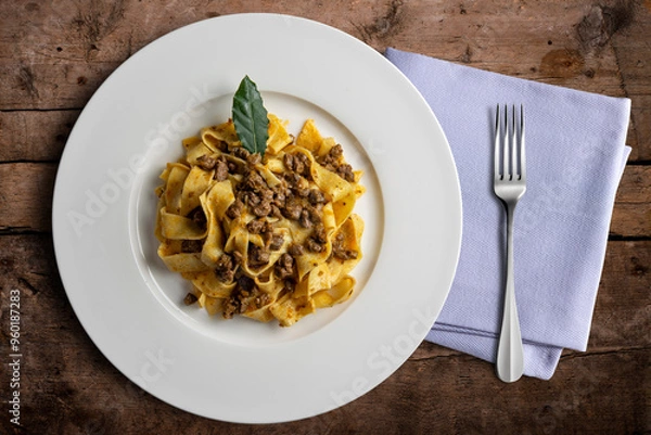 Fototapeta Plate with pappardelle with wild boar ragout sauce with bay leaf and napkin