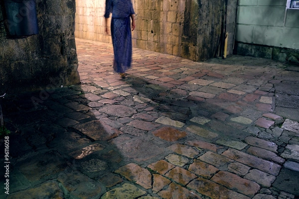 Fototapeta Blurred silthouette of a girl, going from a stone arch