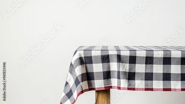 Obraz  A checkered tablecloth is draped over a wooden table, shown against a white background