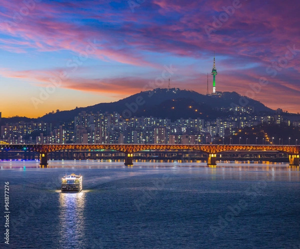 Fototapeta Seoul City after sunset and a sightseeing boat on the Han River and a bridge with Namsan Mountain and Seoul Tower in the background, Seoul, South Korea.