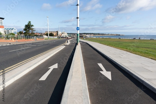 Fototapeta White arrows showing direction of travel painted on cycle paths in seaside location