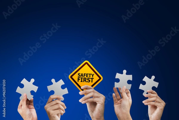 Fototapeta Hand holding safety first symbols and holding puzzle at blue background, Safety first concept.