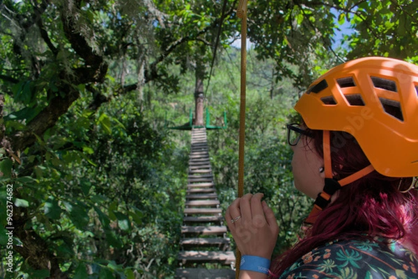 Obraz Adventurous woman in front of a suspension bridge