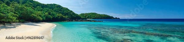 Fototapeta A sweeping view of a tropical coastline with crystal-clear waters gently lapping at a pristine white sandy beach, surrounded by lush greenery under a cloudless sky