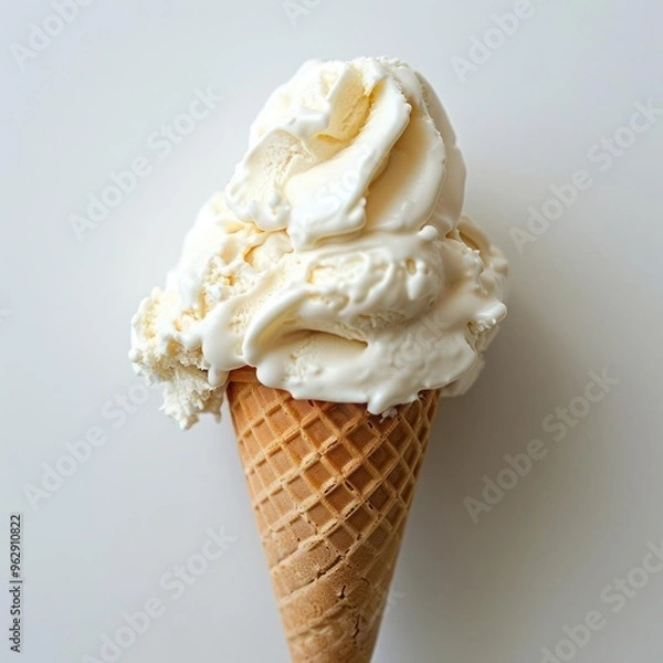 Fototapeta A scoop of vanilla ice cream on a waffle cone, with swirls suggesting it's soft and fluffy.