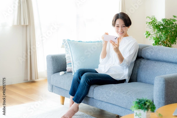 Fototapeta 部屋でスマホを操作するミドル女性