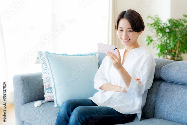 Fototapeta 部屋でスマホを操作するミドル女性