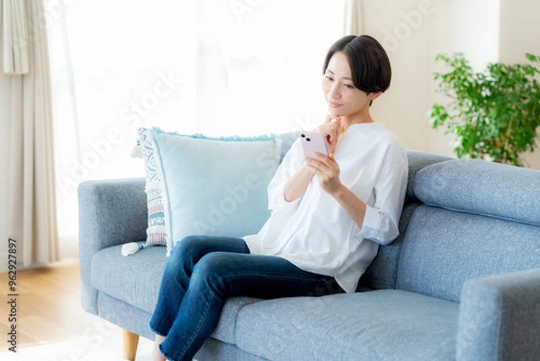 Fototapeta 部屋でスマホを操作するミドル女性
