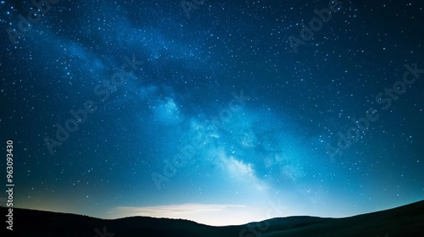 Fototapeta Celestial Tapestry: A breathtaking view of the Milky Way, painting the night sky with its ethereal glow, casting a celestial spell over the rolling hills below. 