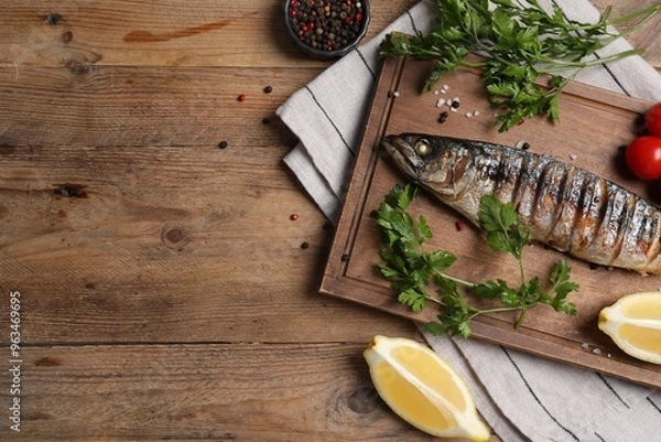 Fototapeta Delicious grilled mackerel, parsley, spices and lemon on wooden table, flat lay. Space for text