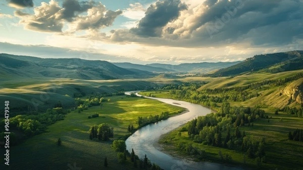 Fototapeta River Winding Through a Lush Valley Under a Cloudy Sky