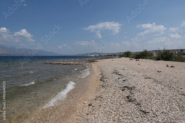 Fototapeta Empty rocky summer beach, bay north of Razanac town, Zadar district, northern Dalmatia, Croatia. End of august 2024 season, clear skies with some cumulus clouds in distance.