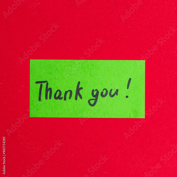 Fototapeta Green small note with the word thank you on a red background