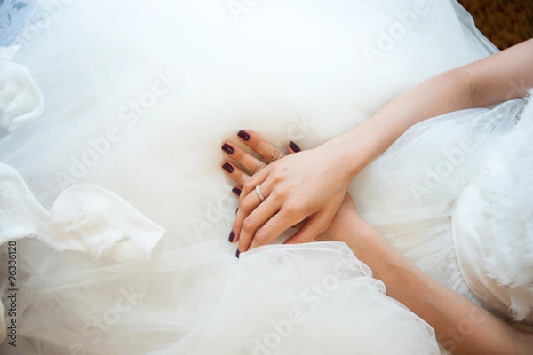 Obraz Hands of the bride with a wedding ring lying on the dress