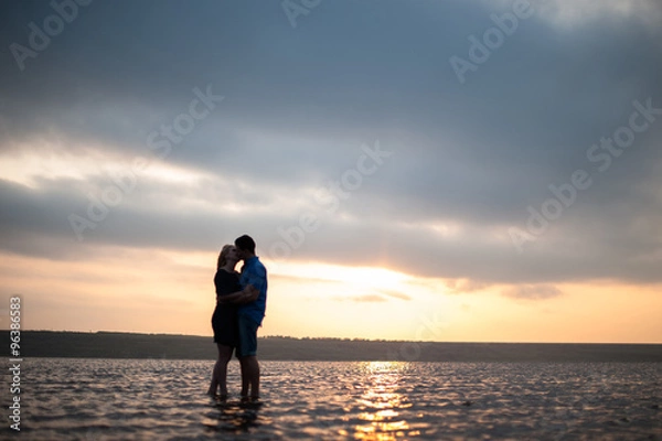 Obraz Loving couple embracing by the sea at sunset