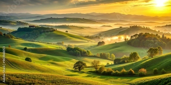 Fototapeta Golden hour captures a serene landscape of rolling hills, with soft, warm light illuminating the misty atmosphere and vibrant green vegetation.