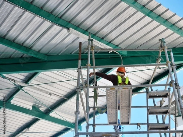 Fototapeta Working at height using personal protective equipment and safety harnesses Working on scaffolding