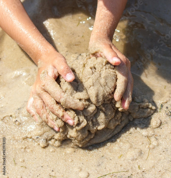 Fototapeta A girl plays in the sand on the seashore