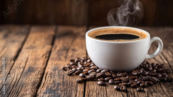 Fototapeta A cup of steaming black coffee with beans scattered around, set on a rustic wooden table.